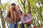 Couple hugging by bicycle in forest