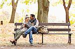 Smiling couple sitting on park bench