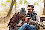 Couple drinking coffee on park bench