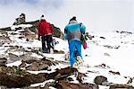 Snowboarders hiking on rocky slope