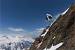 Snowboarder jumping on rocky slope