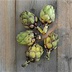 Five artichokes on a wooden surface