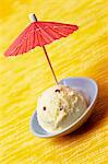 A scoop of peach and mascarpone ice cream decorated with a cocktail umbrella