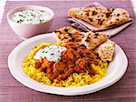 Chicken curry with rice, unleavened bread and a yoghurt dip