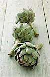 Three artichokes on a wooden surface