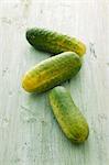 Three gherkins on a wooden surface