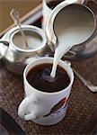 Milk being poured into a cup of coffee