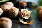 Whole and halved walnuts on a dark surface