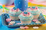 Light blue cupcakes decorated with pink flowers and sugar balls