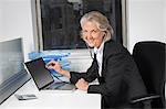 Portrait of senior businesswoman examining laptop with the use of stethoscope at office desk