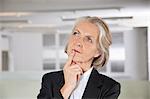 Thoughtful senior businesswoman looking up in office