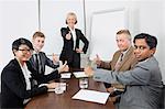 Multiethnic business people giving thumbs up in meeting