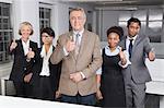 Portrait of multiethnic business group gesturing thumbs up at office