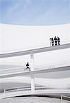 Businessman running up elevated walkway toward business people