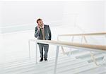 Businessman talking on cell phone at base of stairs