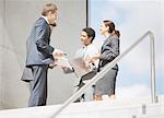 Business people with paperwork meeting at top of stairs