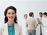 Portrait of smiling businesswoman with doctors in background