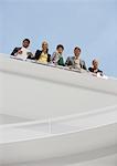 Portrait of smiling business people at railing of elevated walkway