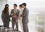 Business people talking at window of conference room