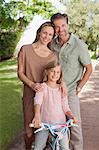 Portrait of smiling parents with daughter on bicycle