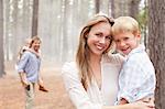 Portrait of smiling mother holding son in woods