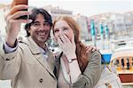 Laughing couple taking self-portrait with camera phone in Venice