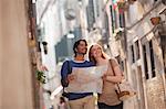Smiling couple with map on narrow street in Venice