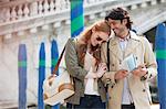 Smiling couple walking with map in Venice