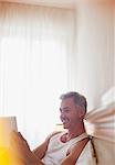Smiling man using digital tablet in bed