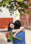 Smiling woman with flowers hugging man