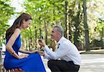 Man with engagement ring proposing to girlfriend in park