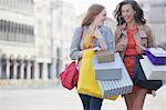 Happy women with shopping bags walking through town square