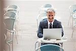 Smiling businessman using laptop at sidewalk cafe