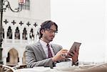 Businessman using digital tablet at sidewalk cafe in Venice