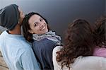 Portrait of smiling woman sitting with friends at lake