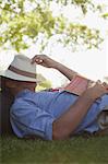 Man napping in grass with book and hat covering face