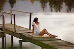 Woman sitting on dock over lake