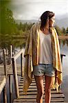 Woman wrapped in blanket standing on dock over lake