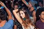 Confident woman dancing in crowd at nightclub