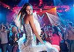 Woman in silver dress with feather boa dancing in nightclub