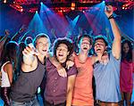 Enthusiastic friends cheering on dance floor of nightclub