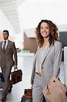 Portrait of smiling businesswoman with suitcase at airport