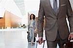 Smiling businesswoman pulling suitcase in airport