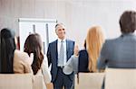 Business people applauding businessman standing at flipchart