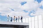 Business people on rooftop balcony looking up at sky