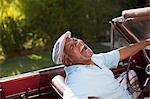 Laughing older man driving convertible