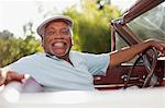 Smiling older man driving convertible