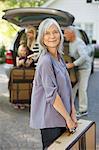 Woman carrying suitcase to trunk