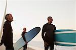 Older surfers carrying boards on beach