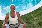 Older woman meditating in backyard